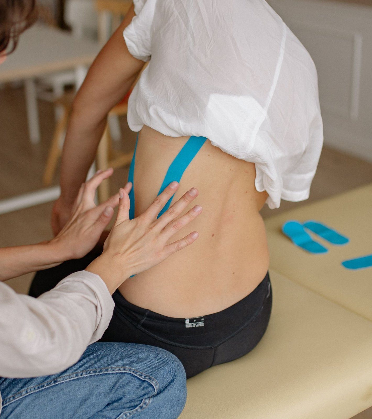 Fisioterapeuta revisando un vendaje neuromuscular en la zona lumbar de una paciente.