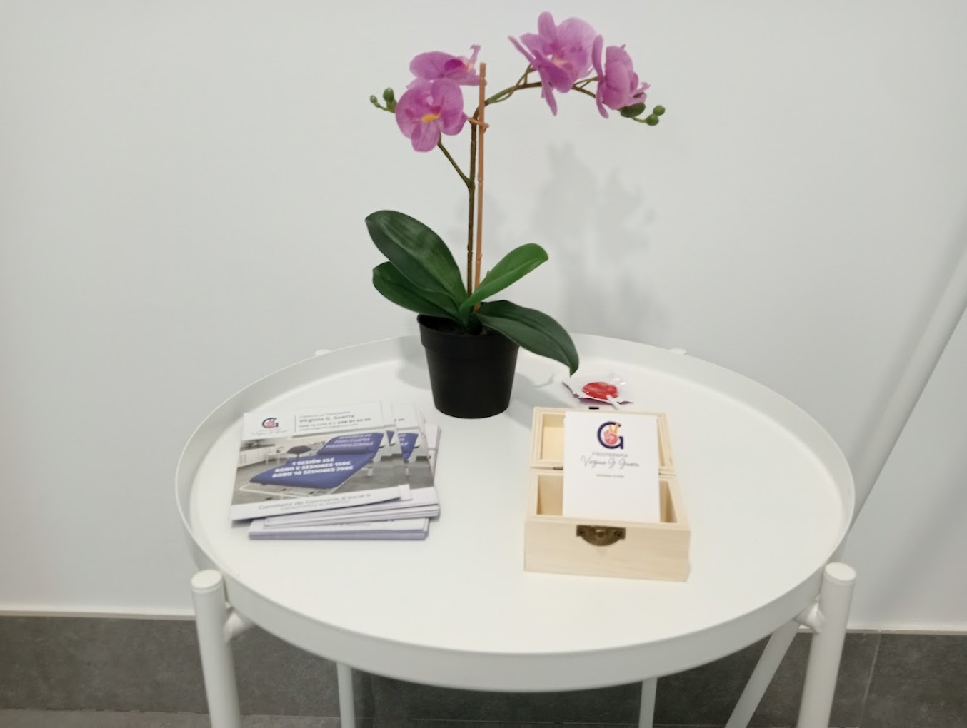 Mesita con folletos y una orquídea en la zona de espera de la consulta.