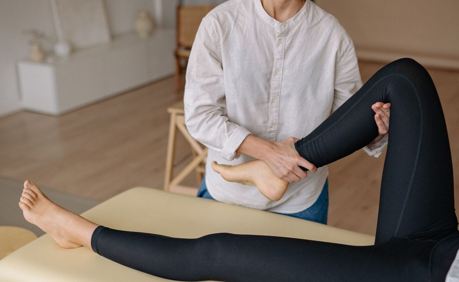Fisioterapeuta flexionando la cadera y la rodilla de una paciente tumbada en camilla.